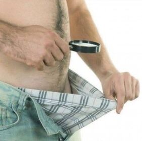 мъж гледа надолу по панталоните си и иска да увеличи пениса си с гел